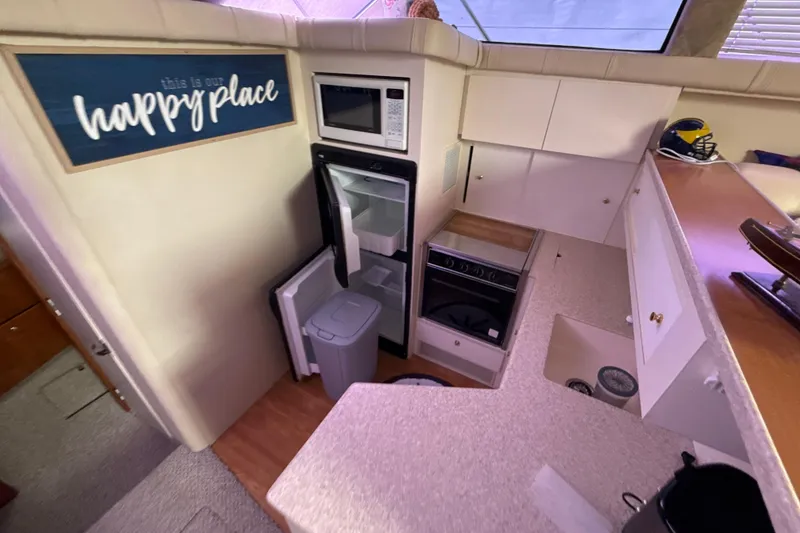 Slide: The Image of Interior of 1999 Silverton 422 Motor Yacht kitchen with appliances and "happy place" sign. - 69