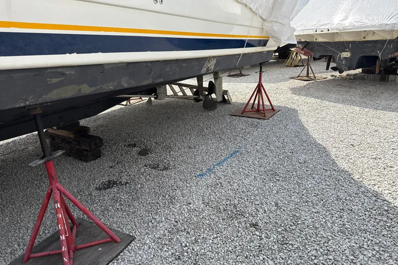 Slide: The Image of 1999 Silverton 422 Motor Yacht on stands for maintenance in a gravel yard. - 95