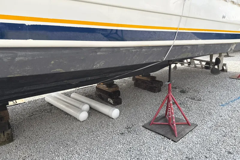 Slide: The Image of 1999 Silverton 422 Motor Yacht on stands, undergoing maintenance on gravel surface. - 96