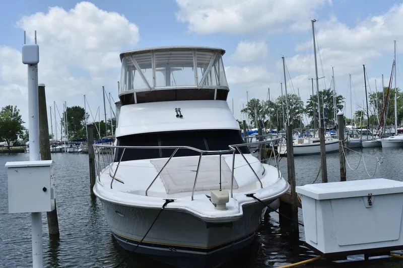 Slide: The Image of 1999 Silverton 422 Motor Yacht docked at marina, surrounded by sailboats under a cloudy sky. - 1