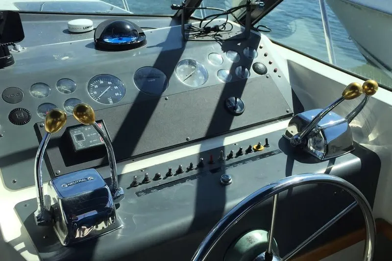 Slide: The Image of Helm of 1989 Tiara Yachts 3100 Open with steering wheel and control levers. - 3