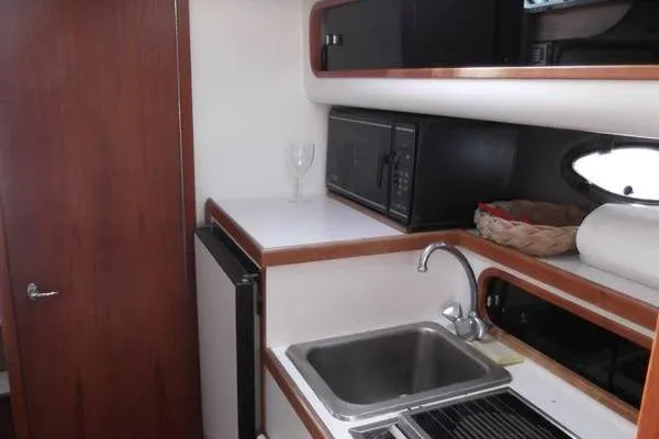 Slide: The Image of 1989 Tiara Yachts 3100 Open galley with sink, microwave, and compact fridge. - 8