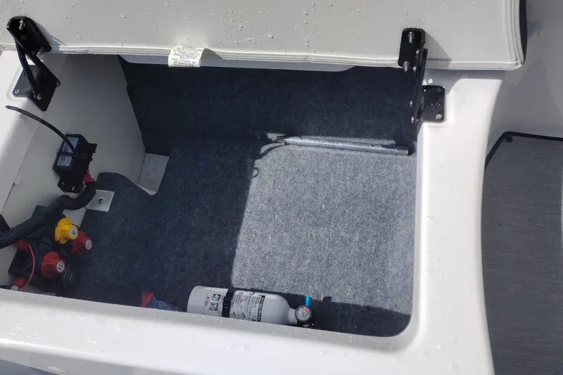 Slide: The Image of Open storage compartment in 2023 Yamaha AR250 boat, featuring safety equipment and wiring. - 28