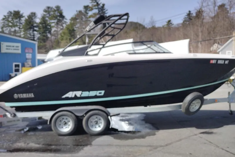 Slide: The Image of 2023 Yamaha AR250 boat on trailer, parked outdoors near trees and buildings. - 4
