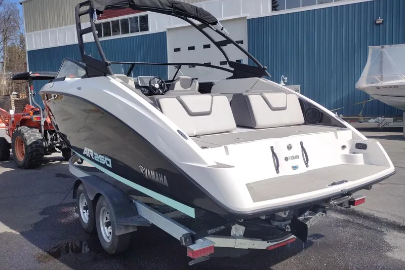 Slide: The Image of 2023 Yamaha AR250 boat on trailer, parked outside a blue building. - 6