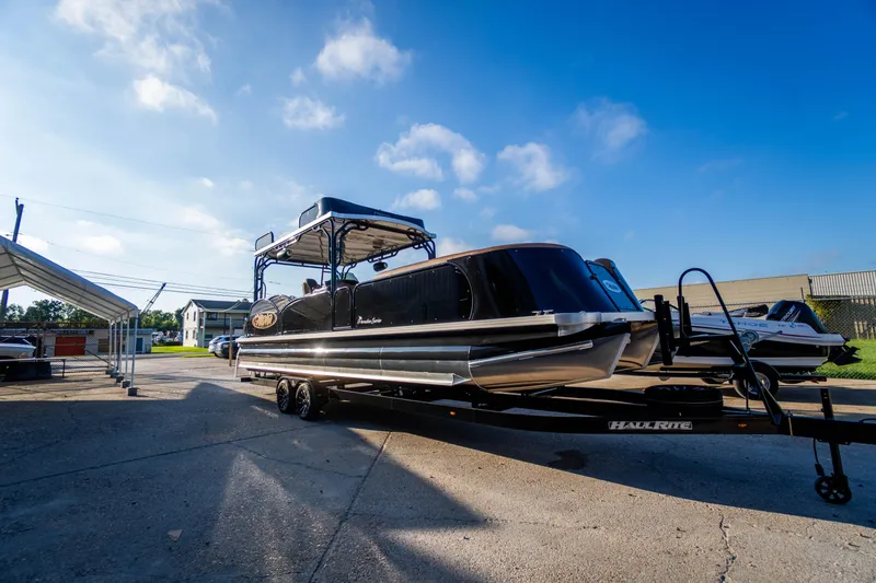 Slide: The Image of 2026 Aloha Paradise 300 Sundeck boat on trailer under clear blue sky. - 2