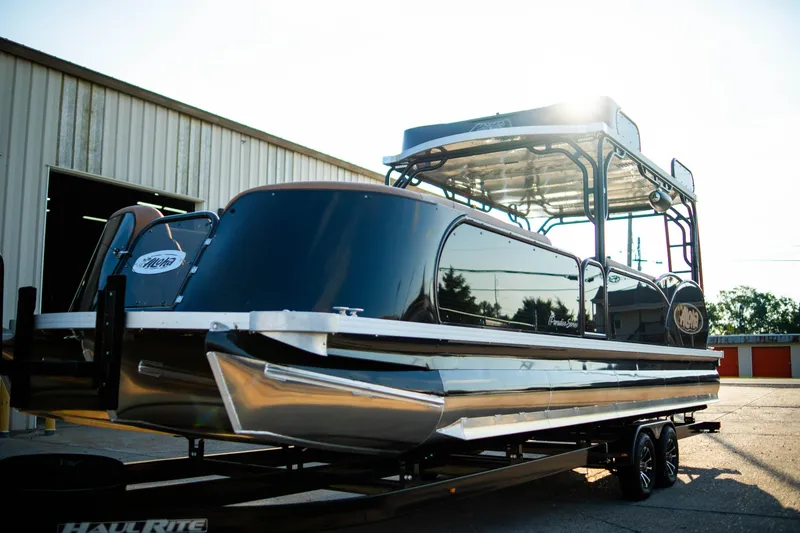 Slide: The Image of 2026 Aloha Paradise 300 Sundeck pontoon boat on trailer, parked outside a warehouse. - 9