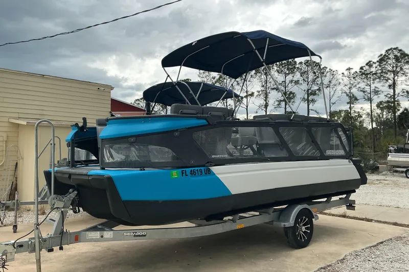 The Image of 2023 Sea-Doo Switch 19 pontoon boat on trailer, blue and white design, parked outdoors. - 0
