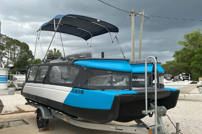 Slide: The Image of 2023 Sea-Doo Switch 19 pontoon boat on trailer under cloudy sky. - 3