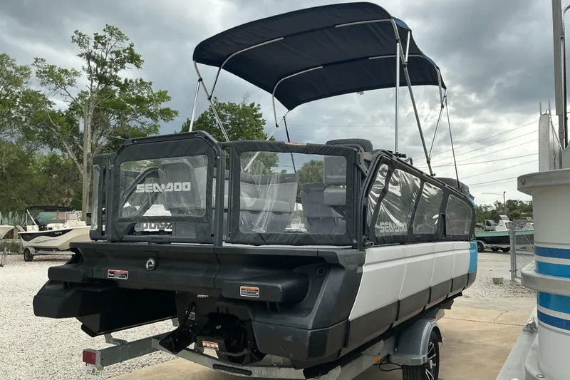 Slide: The Image of 2023 Sea-Doo Switch 19 pontoon boat with canopy, parked outdoors under cloudy skies. - 5