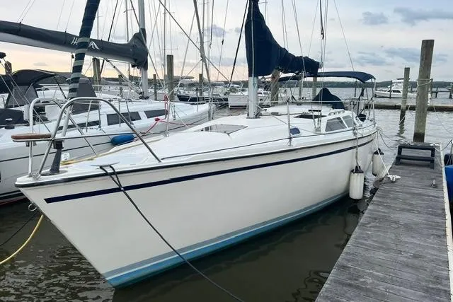 The Image of 1990 Hunter 33.5 sailboat docked at marina, featuring sleek white hull and blue accents. - 0