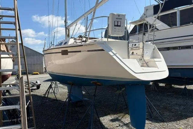 Slide: The Image of 1990 Hunter 33.5 sailboat on stands in a boatyard under a clear blue sky. - 2