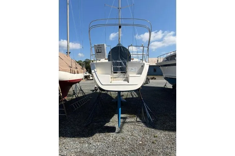 Slide: The Image of 1990 Hunter 33.5 sailboat on stands, viewed from the stern, under a clear blue sky. - 5
