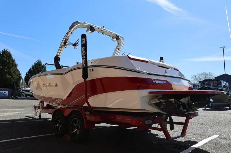 Slide: The Image of 2021 MasterCraft NXT24 boat on trailer, red and white design, parked outdoors. - 10