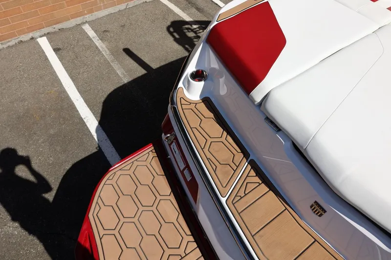 Slide: The Image of 2021 MasterCraft NXT24 boat with red and white upholstery, parked on asphalt. - 16