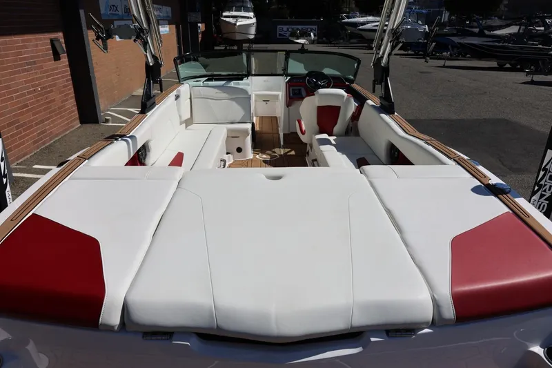 Slide: The Image of 2021 MasterCraft NXT24 boat interior with white and red seating, docked outdoors. - 18
