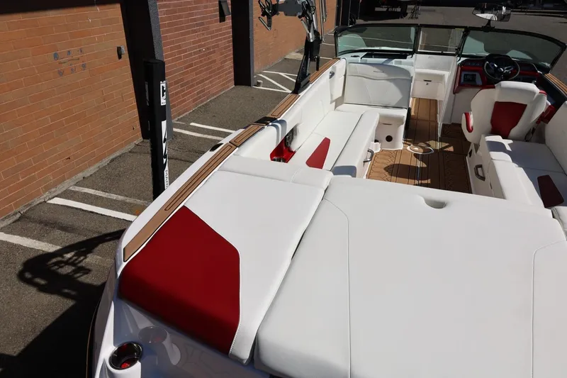 Slide: The Image of 2021 MasterCraft NXT24 boat interior with white and red seating, docked near a brick wall. - 19