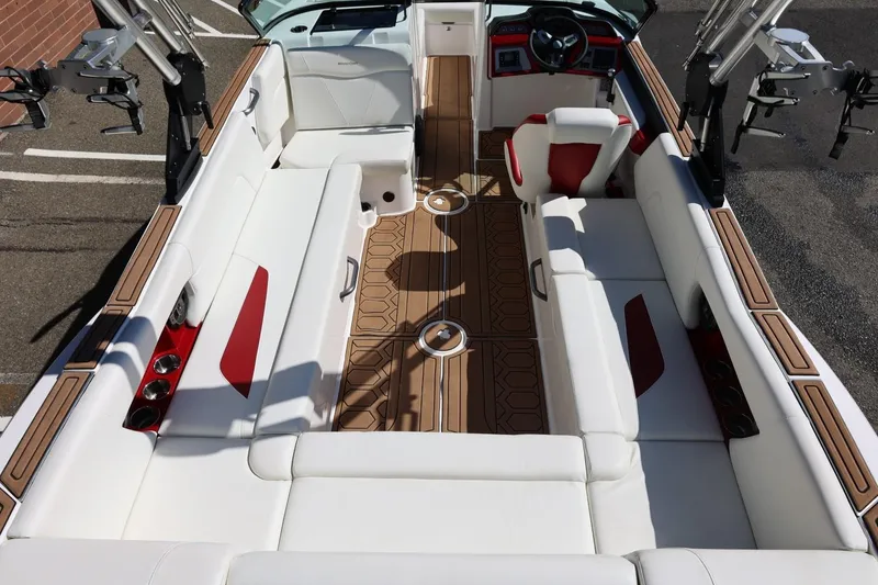 Slide: The Image of 2021 MasterCraft NXT24 boat interior with white and red seating, wood accents, and steering wheel. - 21