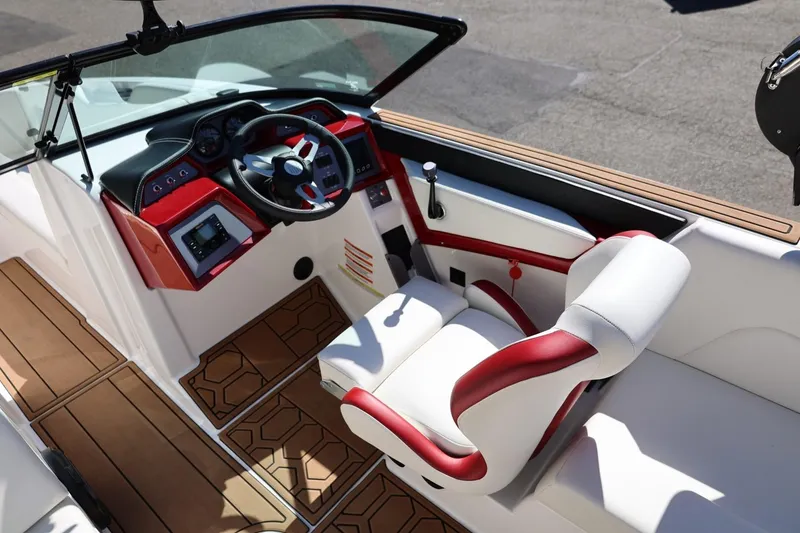 Slide: The Image of 2021 MasterCraft NXT24 boat interior with red and white seating, modern dashboard, and wooden flooring. - 24
