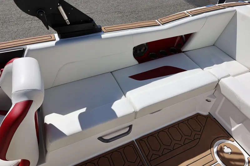 Slide: The Image of 2021 MasterCraft NXT24 boat interior with white and red seating, cup holders, and teak flooring. - 25