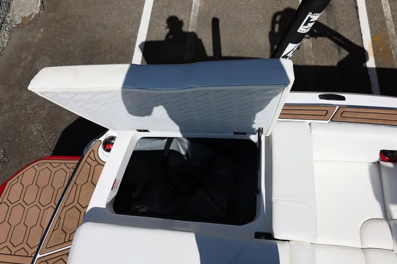 Slide: The Image of 2021 MasterCraft NXT24 boat with open storage compartment, white seating, and brown flooring. - 32