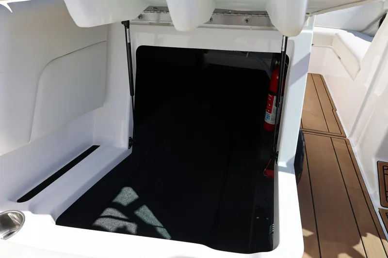 Slide: The Image of 2021 MasterCraft NXT24 boat storage compartment with fire extinguisher, open hatch, and wooden flooring. - 37