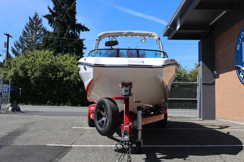 Slide: The Image of 2021 MasterCraft NXT24 boat on trailer, parked outdoors under clear blue sky. - 6