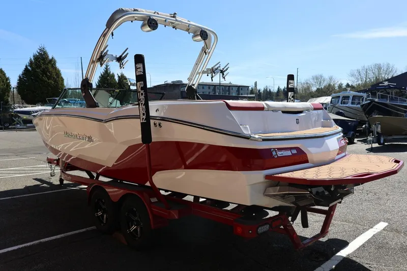 Slide: The Image of 2021 MasterCraft NXT24 boat with red and white design on a trailer in a parking lot. - 9