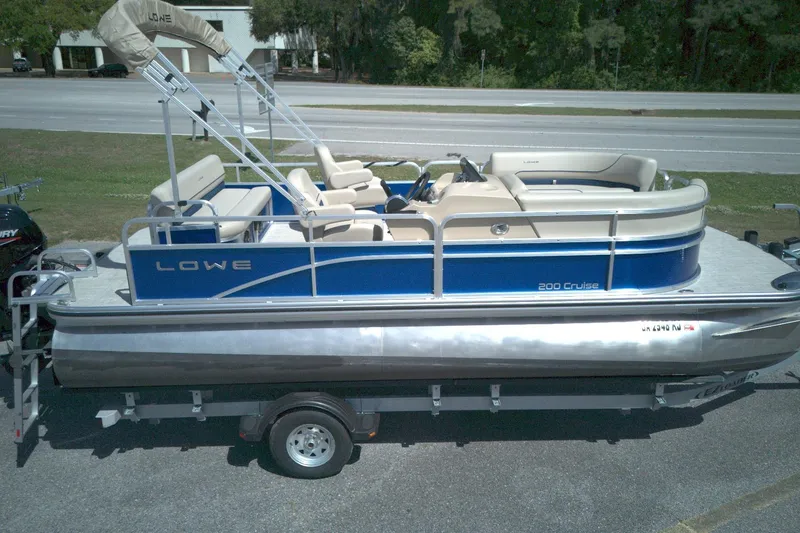 Slide: The Image of 2024 Lowe Ultra 200 Cruise pontoon boat on trailer, blue and beige design. - 10
