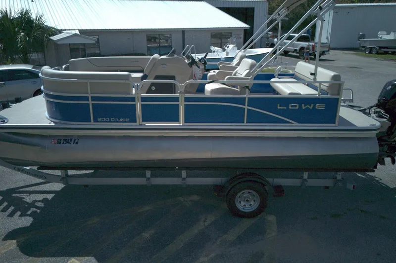 Slide: The Image of 2024 Lowe Ultra 200 Cruise pontoon boat on trailer in a parking lot. - 12