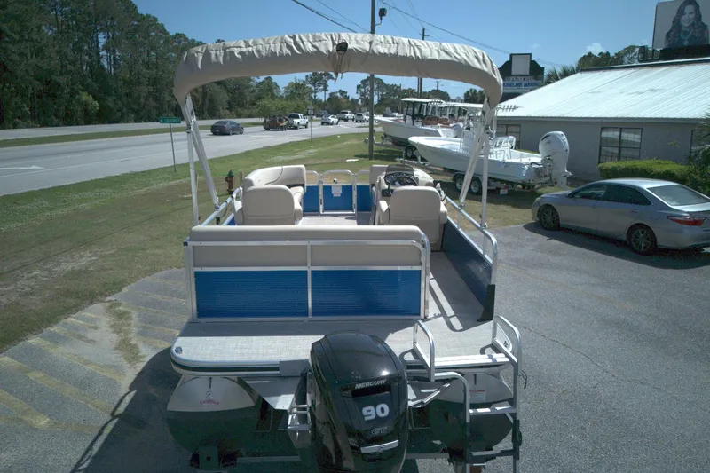Slide: The Image of 2024 Lowe Ultra 200 Cruise pontoon boat with canopy, parked near a road. - 2