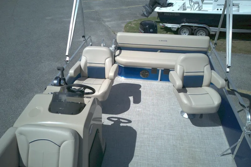Slide: The Image of 2024 Lowe Ultra 200 Cruise pontoon boat interior with beige seating and steering console. - 6
