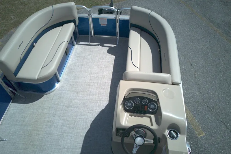 Slide: The Image of 2024 Lowe Ultra 200 Cruise pontoon boat interior with beige seating and steering console. - 7