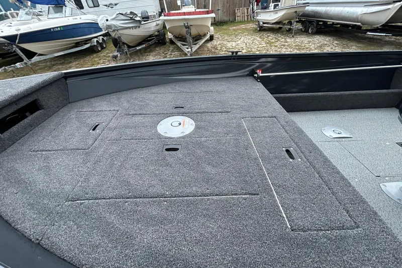 Slide: The Image of 2026 Crestliner 1650 Discovery Tiller boat interior with carpeted deck and storage compartments. - 4