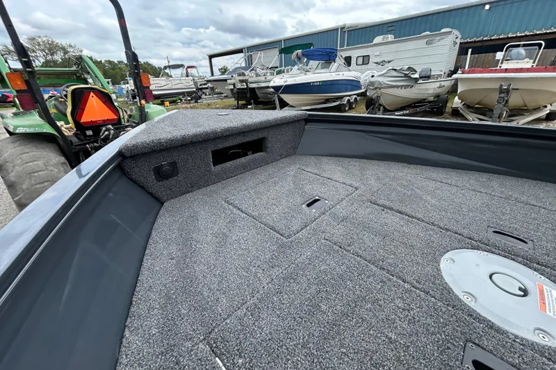 Slide: The Image of 2026 Crestliner 1650 Discovery Tiller boat interior with carpeted deck, parked outdoors. - 5