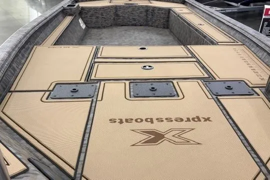 Slide: The Image of 2026 Xpress X18DB boat interior with tan deck and storage compartments. - 3