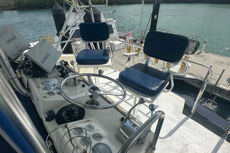 Slide: The Image of 1981 Hatteras 43 Convertible yacht helm with Garmin navigation, docked by the water. - 10