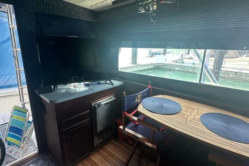 Slide: The Image of Interior of 1981 Hatteras 43 Convertible yacht with TV, table, and marina view. - 16