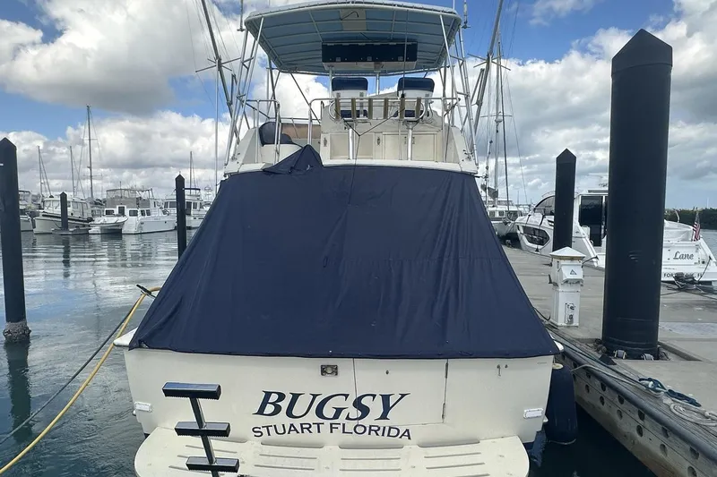 Slide: The Image of 1981 Hatteras 43 Convertible yacht docked, covered, with "Bugsy" and "Stuart Florida" on the stern. - 3