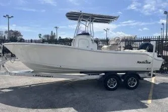 Slide: The Image of 2023 NauticStar 2302 Legacy boat on trailer, parked outdoors under blue sky. - 5
