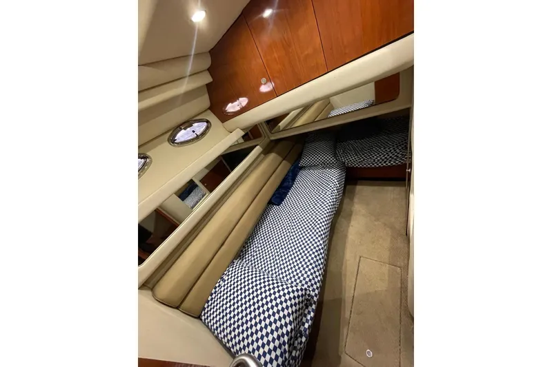 Slide: The Image of 2004 Sea Ray 480 Sedan Bridge cabin with checkered bedding and wooden cabinetry. - 10