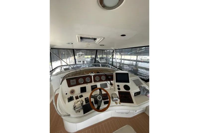 Slide: The Image of 2004 Sea Ray 480 Sedan Bridge helm with modern navigation equipment and wooden steering wheel. - 18