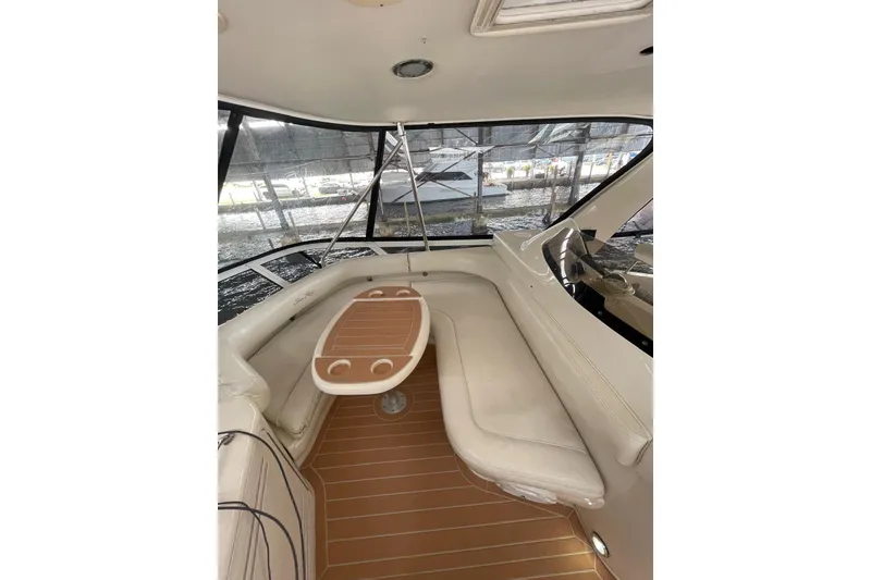 Slide: The Image of 2004 Sea Ray 480 Sedan Bridge interior with seating and table, docked at marina. - 19