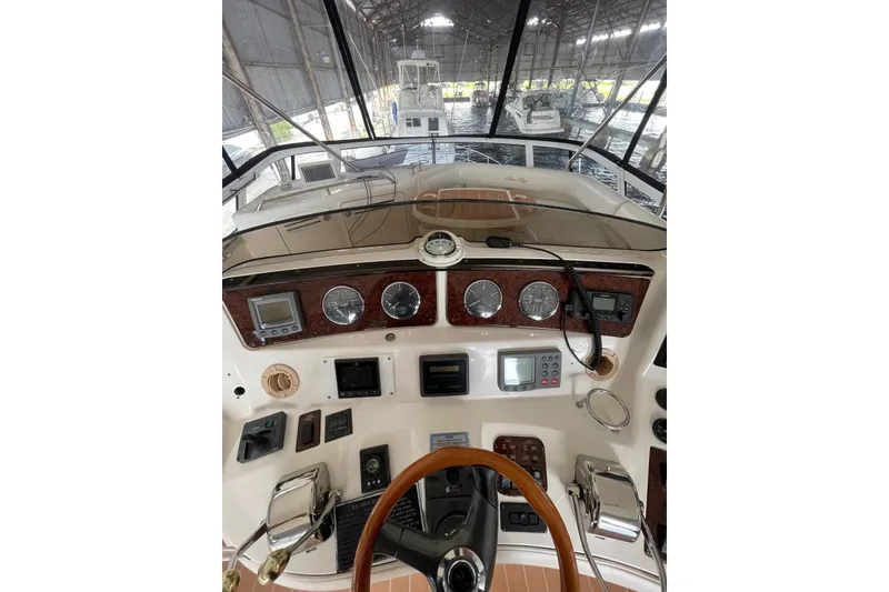Slide: The Image of 2004 Sea Ray 480 Sedan Bridge helm with gauges and controls in a marina setting. - 22