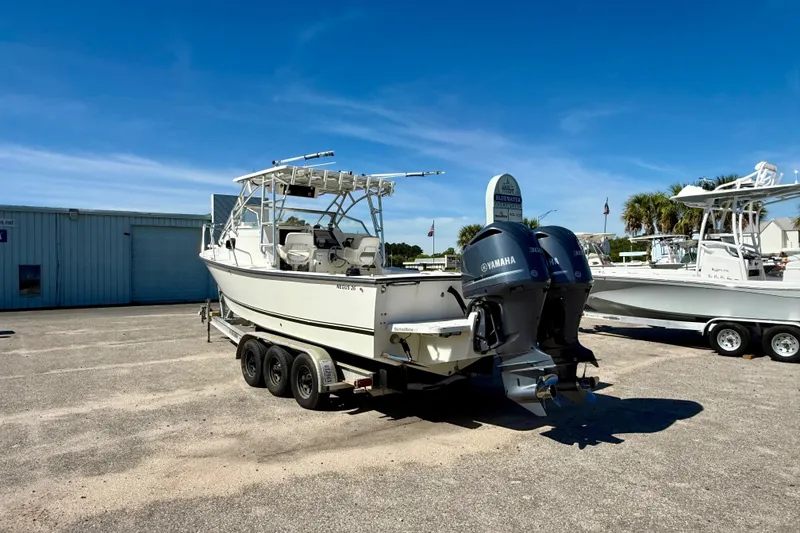 Slide: The Image of 1988 Negus 26 boat with dual Yamaha engines on a trailer, parked outdoors. - 2