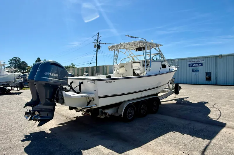 Slide: The Image of 1988 Negus 26 boat with Yamaha engines on a trailer in a sunny outdoor setting. - 4