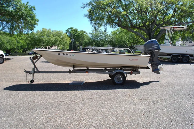 The Image of 1976 Boston Whaler 15 boat on trailer, parked outdoors with trees in background. - 1