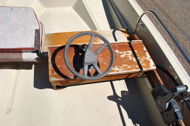 Slide: The Image of 1976 Boston Whaler 15 boat interior with vintage steering wheel and worn wooden console. - 13