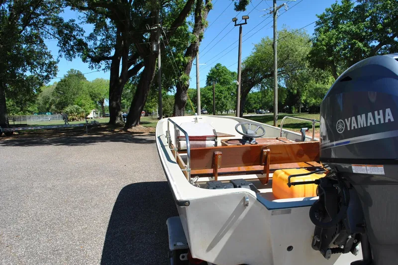 Slide: The Image of 1976 Boston Whaler 15 boat with Yamaha motor in a sunny park setting. - 15