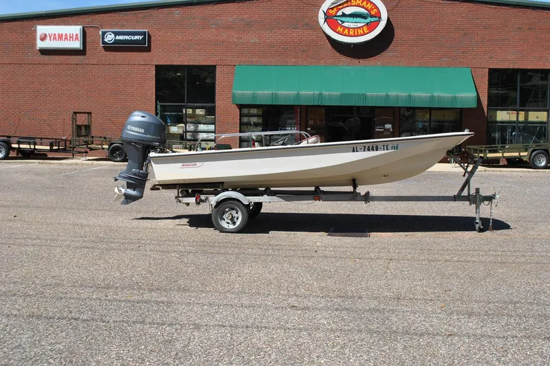 Slide: The Image of 1976 Boston Whaler 15 boat on trailer outside marine store. - 5